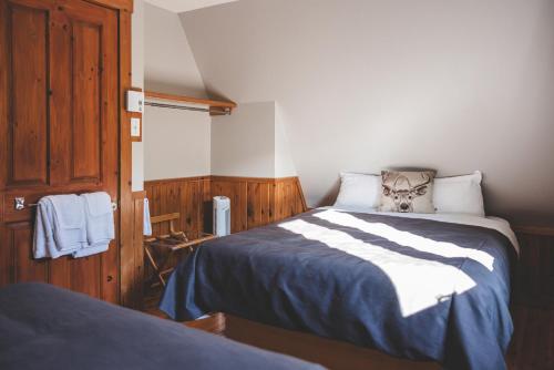 a bedroom with a bed with blue and white sheets at Gîte du Mont-Albert - Sepaq in Sainte-Anne-des-Monts