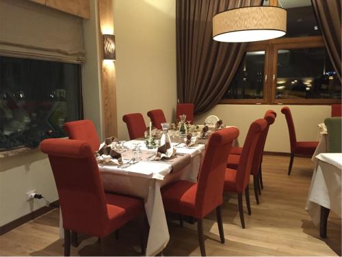 a dining room with a long table and red chairs at Hotel Nigritella in Selva di Cadore