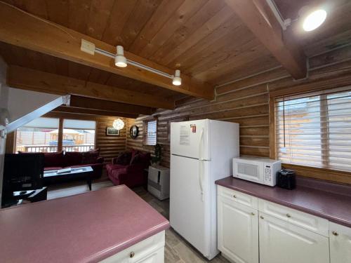 a kitchen with a white refrigerator and a living room at Talkeetna Log Cabin with Hot Tub Unit 2 in Talkeetna