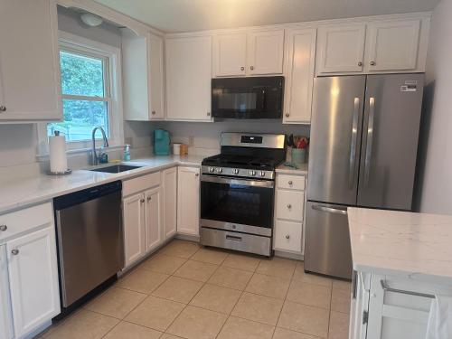 Una cocina con gabinetes blancos y electrodomésticos de acero inoxidable. en 4 Bedroom Cape Getaway, 5 Min Drive to Beach, Pool Table, Grill, Backyard, en Falmouth