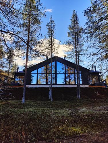 a house on a hill with trees in the foreground at Villa Arctic Trail B - Lapland Escape with Outdoor Hot Tub & Ylläs Ski Passes in Äkäslompolo