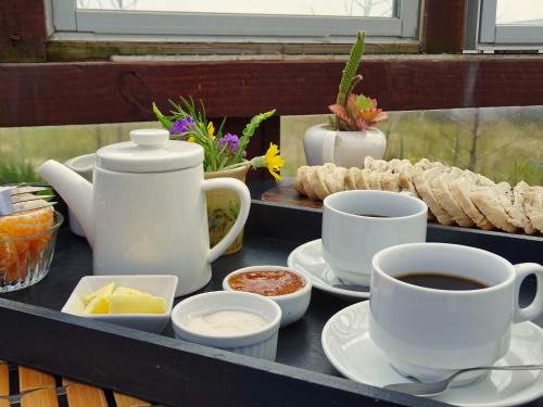 a tray with cups of coffee and some food at Carmela Suites Cabo Polonio in Cabo Polonio