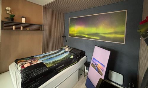 a bedroom with a bed with a painting on the wall at New Aurora Hotspot - Studio Nordspissen in Tromsø