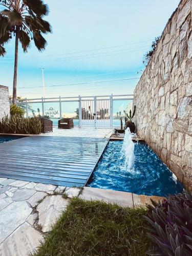 a swimming pool with a fountain in front of a wall at Mandai Apartamentos in Cabo Frio