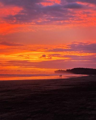 two people standing on the beach at sunset at Bambuk Bio Chalet Uvita Beach Front in Uvita