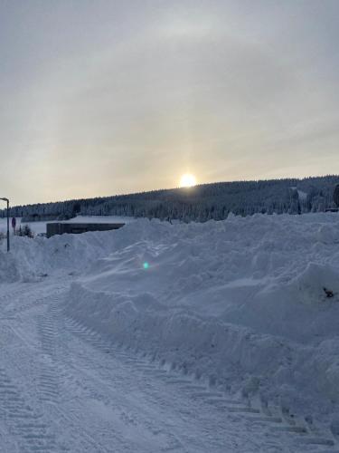 a snow covered field with the sun setting in the background at Horská chata LADA in Loučná pod Klínovcem