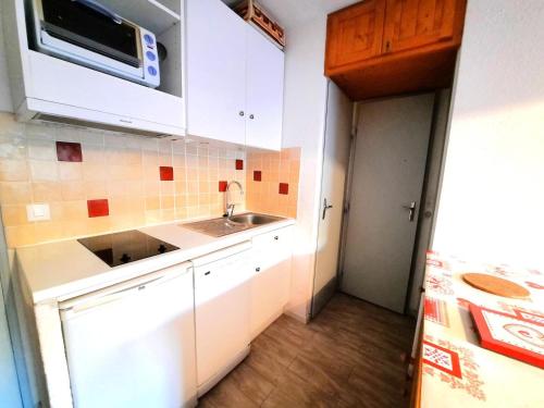 une petite cuisine avec un évier et un micro-ondes dans l'établissement Résidence Jetay - Appartement 4 personnes aux Ménuires MAE-5564, aux Menuires