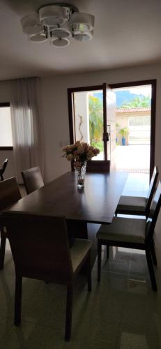 a dining room table with chairs and a vase of flowers on it at Pousada Araúna Angra in Angra dos Reis