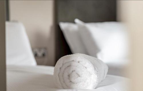 a roll of white towels sitting on a bed at Lodge 17 St Andrews in St. Andrews