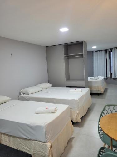 a room with three beds and a table and chairs at Victory Flat&Hotel in João Pessoa