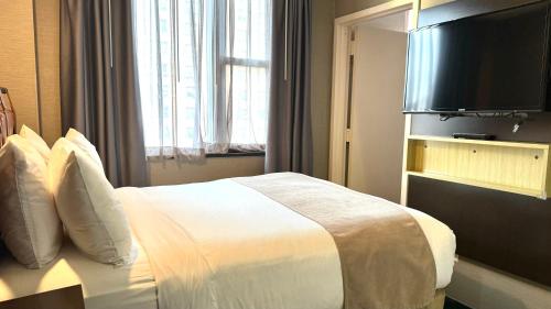 a hotel room with a bed and a flat screen tv at Madison LES Hotel in New York