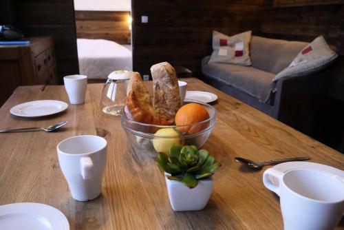 une table avec un bol de pain et une orange dessus dans l'établissement Résidence Cembros - CEMBROS 31 MAE-6251, à Les Allues