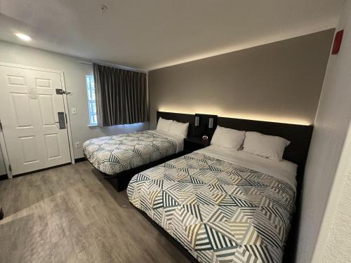 a hotel room with two beds and a door at Studio 6 Columbus GA Columbus Airport in Columbus