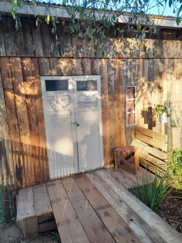 a wooden shed with a door and a bench at Cabana SERENA in Santana do Livramento