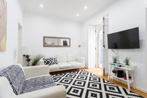 a white living room with a white couch and a tv at São Vicente Bedrooms in Lisbon