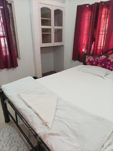 two beds in a room with red curtains at kirtti inn AC double in Guwahati