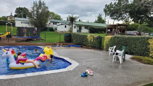 a pool with two children playing on a unicorn inflatable at Waitomo TOP 10 Holiday Park in Waitomo Caves