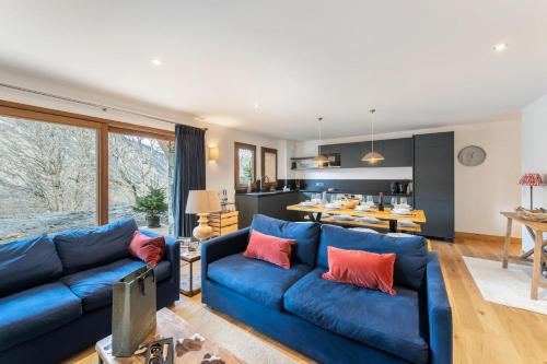 un salon avec un canapé bleu et une cuisine dans l'établissement Les Chalets Du Cheval Noir - Construction neuve proche de toutes les commodités MAE-6441, à Saint-Martin-de-Belleville