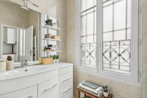 une salle de bain avec un lavabo, un miroir et une fenêtre dans l'établissement Charming Apartment 1 BR 4 persons - Opera Bourse, à Paris