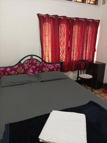 a bedroom with a bed with red curtains at kirtti inn AC double in Guwahati