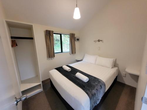 a bedroom with a bed with two towels on it at Waitomo TOP 10 Holiday Park in Waitomo Caves