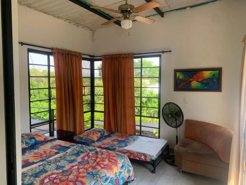 a bedroom with a bed and a chair and windows at Melgar Alojamiento Villa Claudia in Melgar
