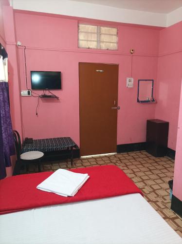 a room with a pink wall with a door and a table at kirtti inn AC double in Guwahati