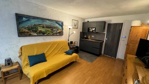 un salon avec un canapé jaune et une cuisine dans l'établissement Résidence Chamoisiere - Joli studio proche des pistes et des commerces. Parking MAE-7401, à Montgenèvre