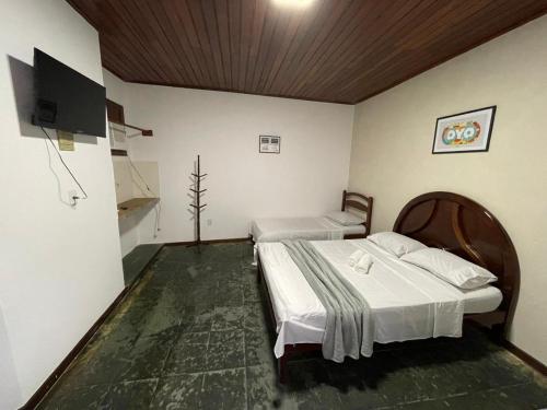 a bedroom with two beds and a flat screen tv at Pousada Terra Do Sol in Arraial do Cabo
