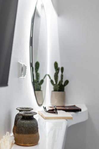 a mirror and a table with a book and a vase at Anatoli Hotel in Naxos Chora
