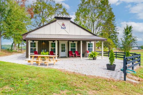 a cottage with a picnic table and red chairs at Loretto Cottage on Bourbon Trail with Fire Pit in Loretto