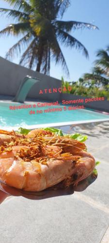 a sandwich on a plate with a palm tree in the background at Casa Com Piscina. Prox. Mar e Lagoa Ideal Família in Marataizes