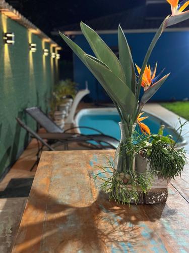 a vase with flowers on a table next to a pool at Vila Verde Chalés-Serro in Sêrro