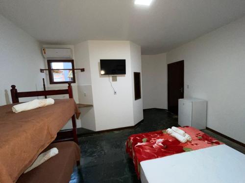 a hospital room with two beds and a tv at Pousada Terra Do Sol in Arraial do Cabo