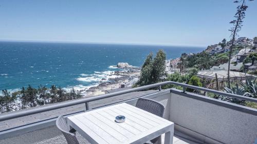 Una mesa y sillas en un balcón con vista al mar. en Dei Templi Apart Hotel, en Viña del Mar