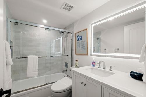 a bathroom with a toilet and a sink and a shower at Serenity Shores Renovated Top Floor Condo w Stunning Ocean Views in New Smyrna Beach
