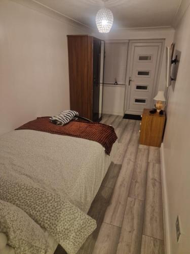 Un dormitorio con una cama y suelo de madera y una puerta. en Sariyu space studio flat with own bathroom and Kichen, en Rainham
