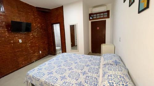 a bedroom with a bed and a brick wall at Pousada Terra Do Sol in Arraial do Cabo