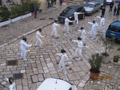a group of people dressed in white dancing on a street at Sax Barisano in Matera