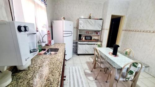 a kitchen with a refrigerator and a table with chairs at Casa em Condomínio com Piscina Privativa in Araruama