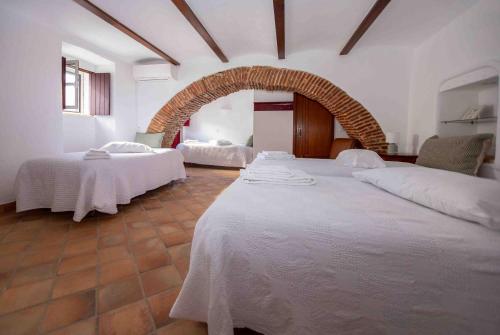 a room with two beds with white sheets and an arch at Refúgio Alentejano in Alandroal