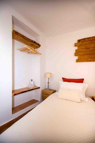 a bedroom with a white bed with a wooden headboard at Refúgio Alentejano in Alandroal