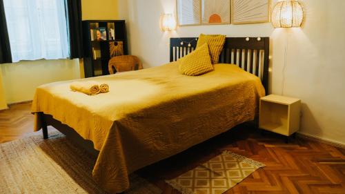 a bedroom with a large bed with a yellow blanket at NAPartman Pécs in Pécs