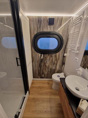 ein Badezimmer mit Waschbecken, Toilette und Fenster in der Unterkunft Hausboot -Berlin WaterBliss in Berlin