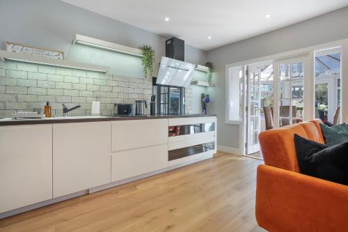 a kitchen with white cabinets and an orange chair at The Northern House - Grampian Lettings in Aberdeen