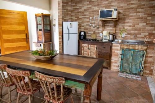 a kitchen with a wooden table and a refrigerator at Apartamentos exclusivos e equipado com varanda ou terraço com Pôr do sol, cozinha privativa, Wi-Fi 600MBs, a 700m da praia de Itapirubá e 1km da BR-101 in Imbituba