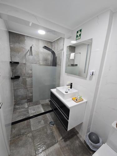 a white bathroom with a sink and a shower at City Centre Apartment Setubal in Setúbal