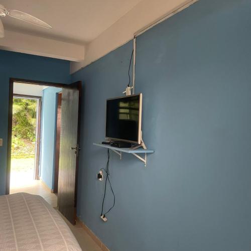 a bedroom with a tv on a blue wall at Solaris do Una in São Sebastião