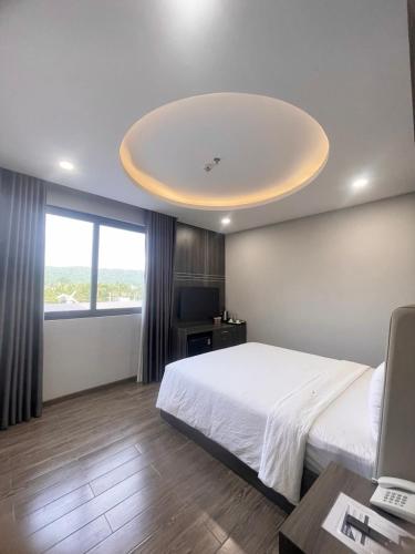 a bedroom with a large white bed and a large window at Le Anh Hotel in Phu Quoc
