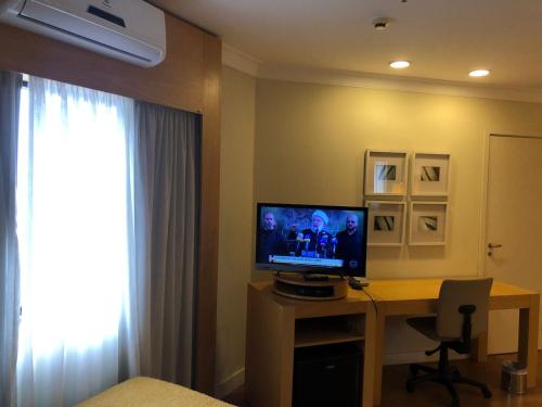 a room with a desk with a television and a window at Flat Nobilis confortavel em frente ao Aeroporto Congonhas - H305 in Sao Paulo